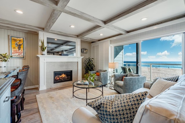 living room with coffered ceiling, light hardwood / wood-style flooring, beamed ceiling, and a water view