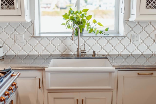 kitchen featuring white cabinetry, sink, tasteful backsplash, and stove