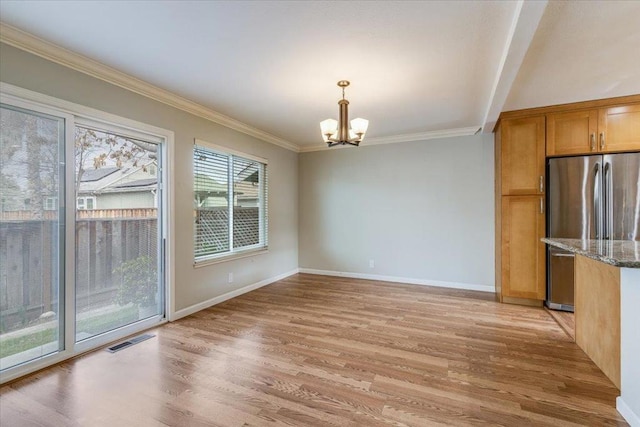 unfurnished dining area featuring crown molding, a chandelier, and light hardwood / wood-style flooring