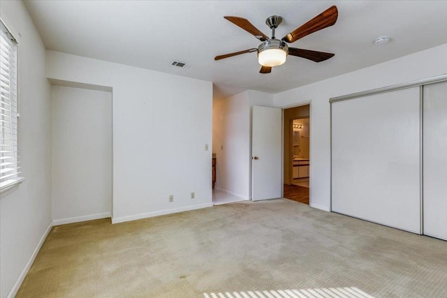 unfurnished bedroom with multiple windows, light colored carpet, ceiling fan, and a closet