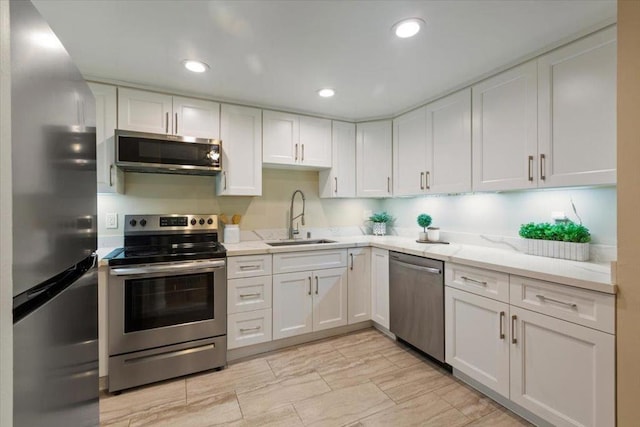 kitchen featuring stainless steel appliances, white cabinetry, light stone countertops, and sink