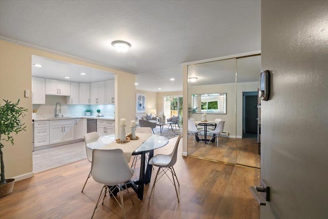 dining space with sink, hardwood / wood-style flooring, and a textured ceiling