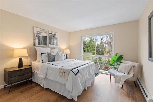 bedroom with a baseboard heating unit and hardwood / wood-style floors