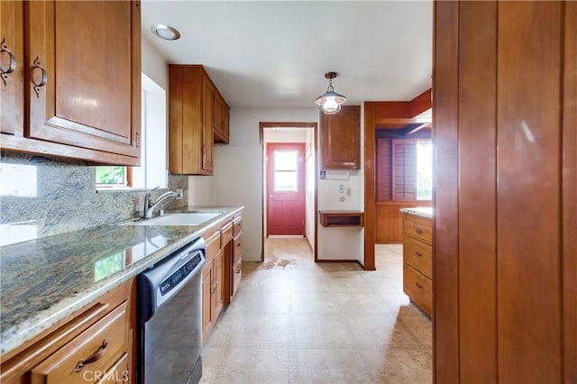 kitchen featuring sink, light stone counters, dishwasher, pendant lighting, and decorative backsplash