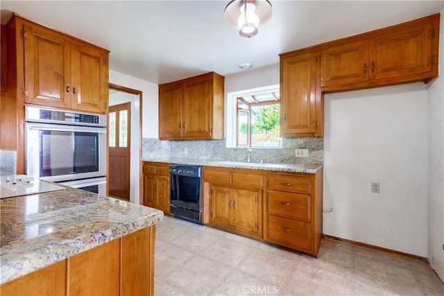 kitchen featuring tasteful backsplash, sink, light stone counters, and black appliances