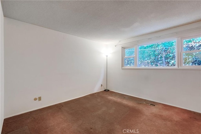 spare room with dark carpet and a textured ceiling