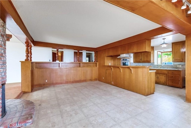 kitchen with a breakfast bar, sink, wooden walls, kitchen peninsula, and pendant lighting