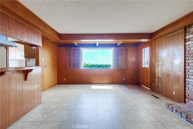 interior space featuring a wealth of natural light, a textured ceiling, and wooden walls