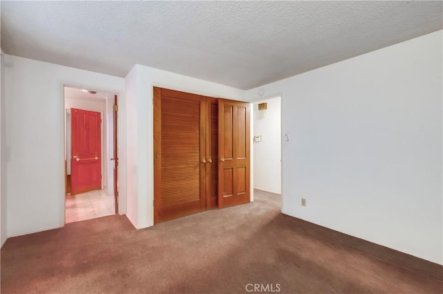 unfurnished bedroom with dark colored carpet, a textured ceiling, and a closet