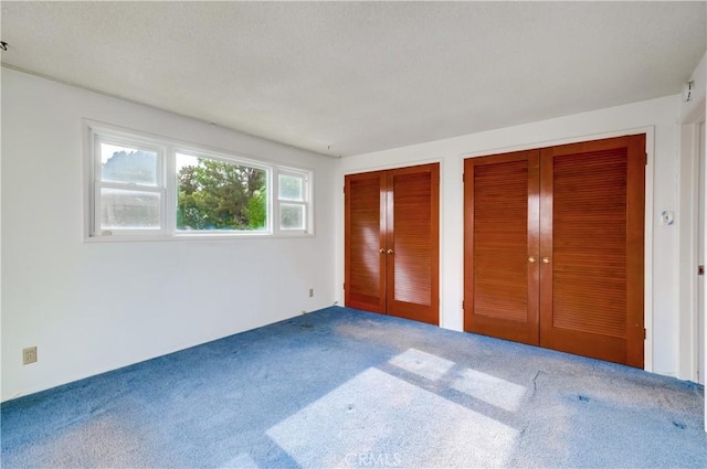 unfurnished bedroom featuring multiple closets and carpet floors