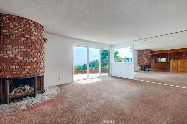 unfurnished living room featuring a fireplace, a textured ceiling, and carpet flooring