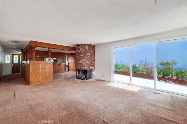 unfurnished living room featuring light carpet, a textured ceiling, and a fireplace