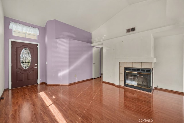 entryway with a tiled fireplace, hardwood / wood-style flooring, and high vaulted ceiling