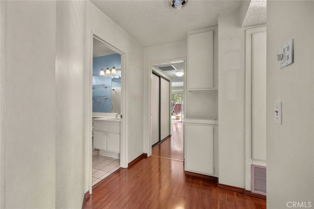 hall featuring wood-type flooring and a textured ceiling