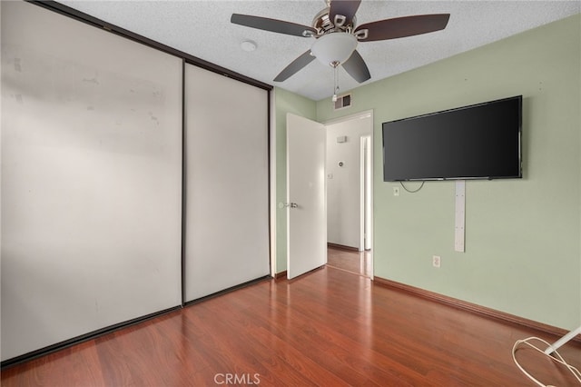 unfurnished bedroom with ceiling fan, a closet, hardwood / wood-style floors, and a textured ceiling