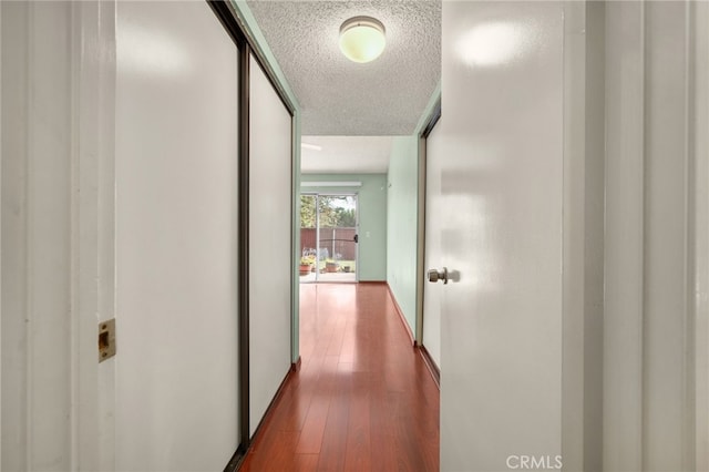 hallway with wood-type flooring and a textured ceiling