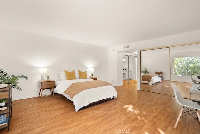 bedroom with hardwood / wood-style floors and two closets