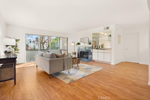 living room featuring a tile fireplace and light wood-type flooring