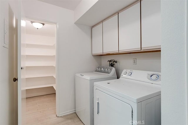 laundry area with cabinets, washer and clothes dryer, and light wood-type flooring