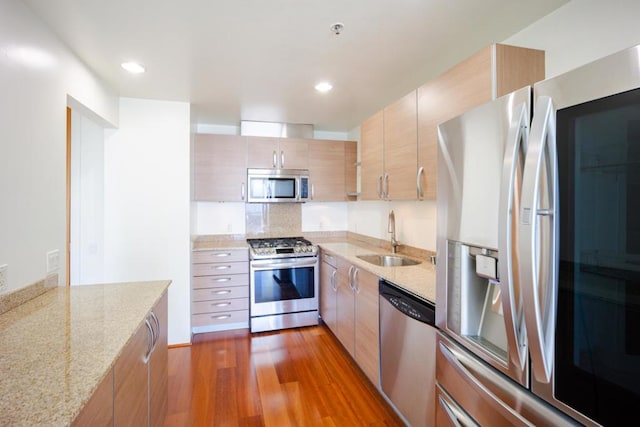 kitchen with stainless steel appliances, dark hardwood / wood-style flooring, sink, and light stone counters