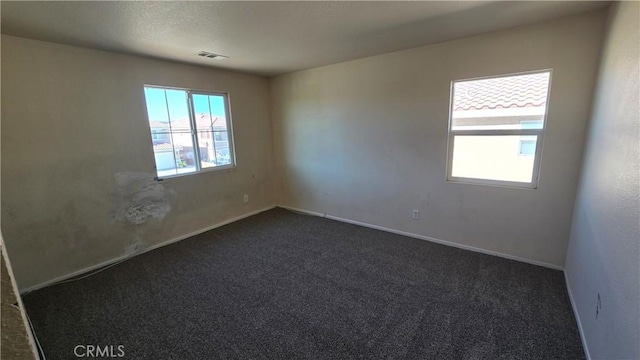 spare room featuring dark colored carpet