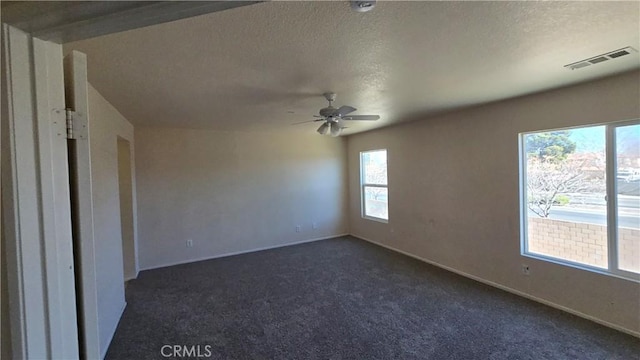 carpeted spare room featuring ceiling fan and a textured ceiling