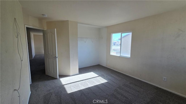 unfurnished bedroom with a closet and dark colored carpet