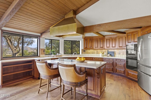 kitchen with a kitchen island, a breakfast bar, backsplash, stainless steel fridge, and light hardwood / wood-style floors