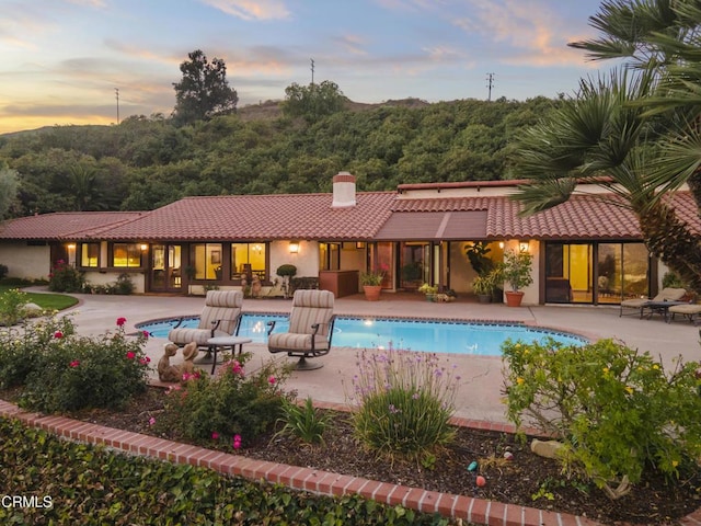 pool at dusk featuring a patio area