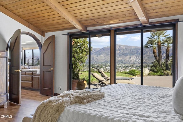 bedroom featuring light hardwood / wood-style flooring, beam ceiling, a mountain view, access to outside, and wooden ceiling