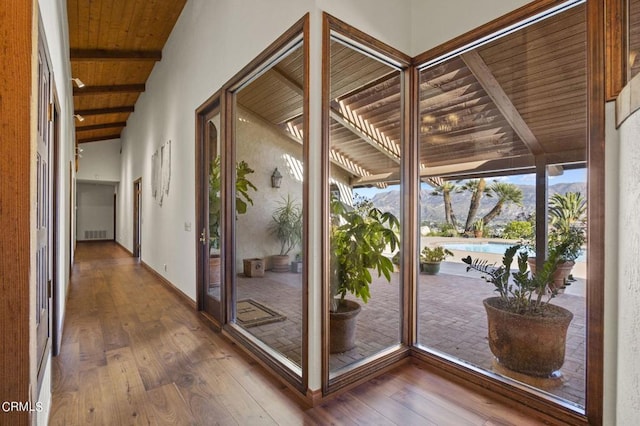 entryway with wood ceiling, a mountain view, hardwood / wood-style flooring, and beamed ceiling