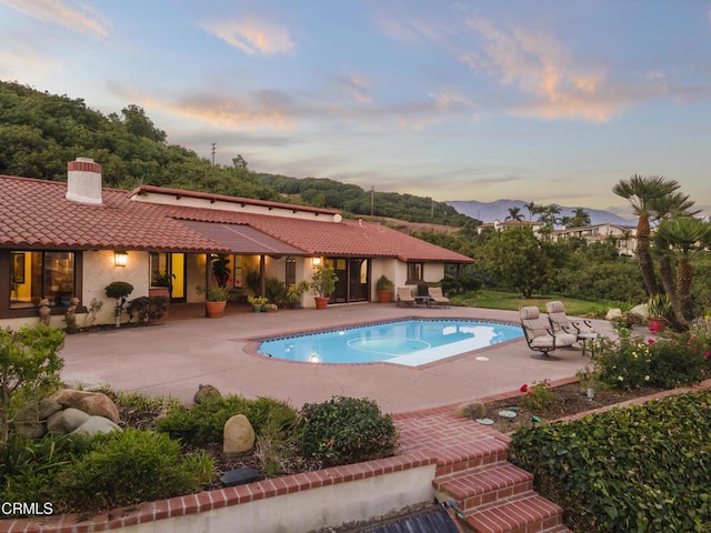 pool at dusk featuring a patio area