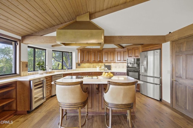 kitchen with wine cooler, a breakfast bar, vaulted ceiling with beams, a center island, and black appliances