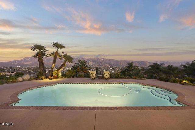 pool at dusk featuring a mountain view