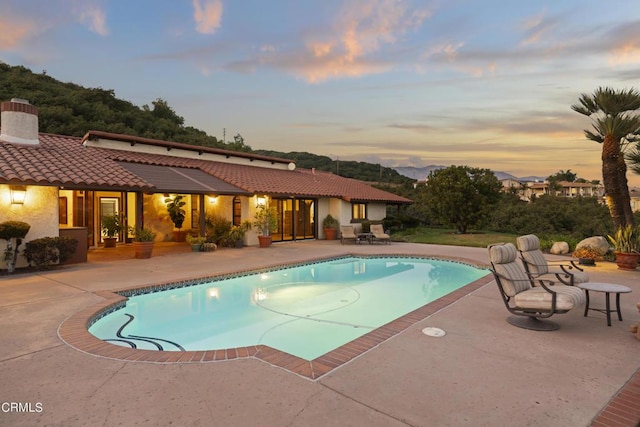 pool at dusk featuring a patio area