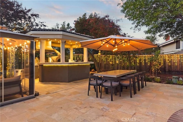 patio terrace at dusk featuring outdoor dining area and fence