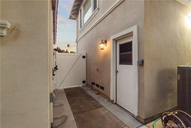 entrance to property featuring a gate, cooling unit, and stucco siding