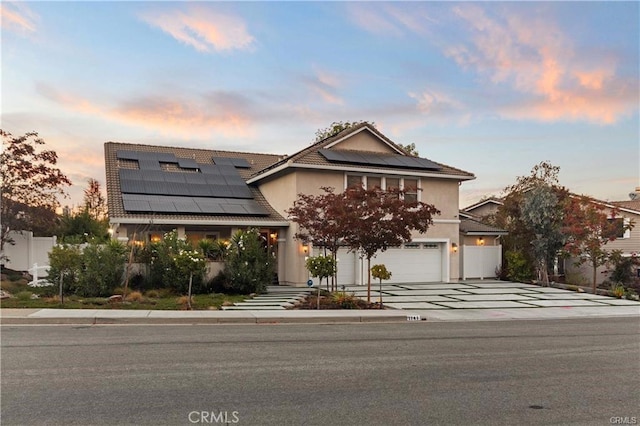 view of front of house featuring solar panels, concrete driveway, a garage, and stucco siding