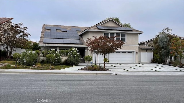 view of front of house with solar panels, driveway, a garage, and stucco siding