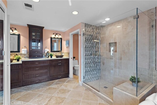 bathroom with tasteful backsplash, visible vents, a shower stall, toilet, and vanity