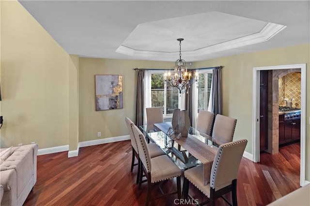 dining area with a notable chandelier, baseboards, a raised ceiling, and dark wood-type flooring