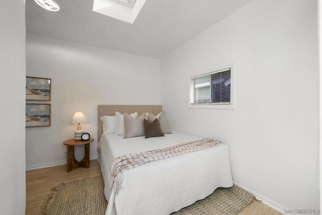 bedroom featuring hardwood / wood-style flooring and a skylight