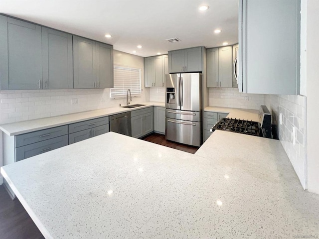 kitchen featuring sink, gray cabinets, kitchen peninsula, stainless steel appliances, and decorative backsplash