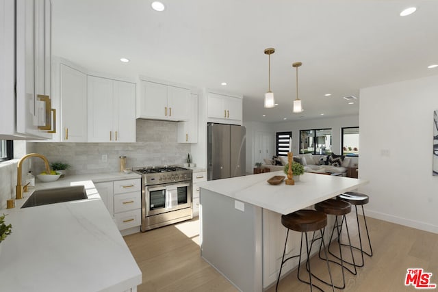 kitchen featuring white cabinetry, sink, stainless steel appliances, and a kitchen island