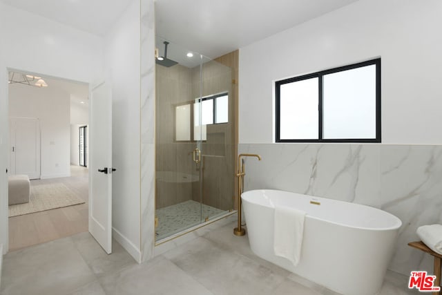 bathroom featuring tile patterned flooring, shower with separate bathtub, and tile walls