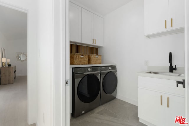 washroom featuring cabinets, sink, and washing machine and dryer