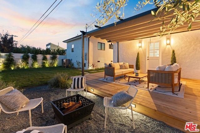 patio terrace at dusk featuring a yard, an outdoor living space with a fire pit, and a deck