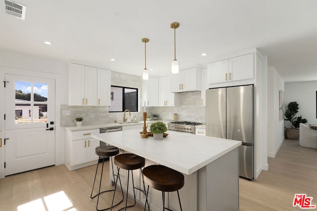 kitchen with stainless steel fridge, range, white cabinetry, a center island, and light wood-type flooring