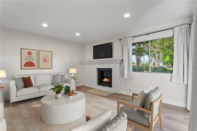 living room with a brick fireplace and hardwood / wood-style flooring