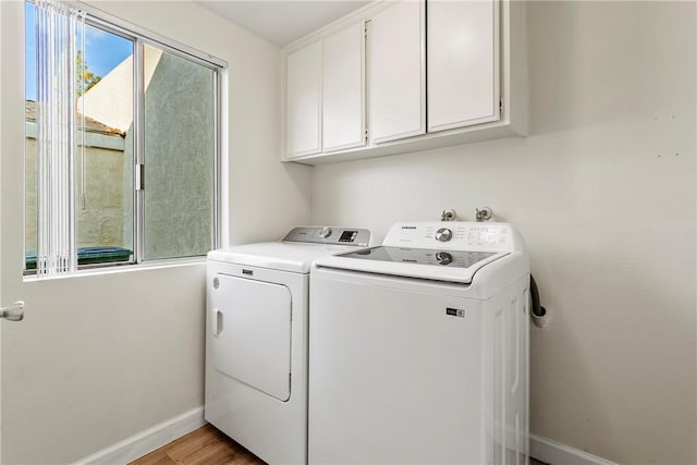 laundry area with cabinets, washer and dryer, and light hardwood / wood-style flooring